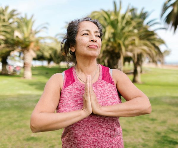 Person smiling and stretching outdoors in a park.